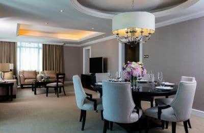 Contemporary living and dining rooms with a circular, dark wood dining table, gray walls, white molding and tan sofas