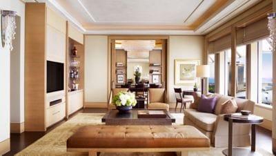 Rectilinear living room with a sofa, bench and chairs around a square coffee table, plus a wet bar and view to dining room