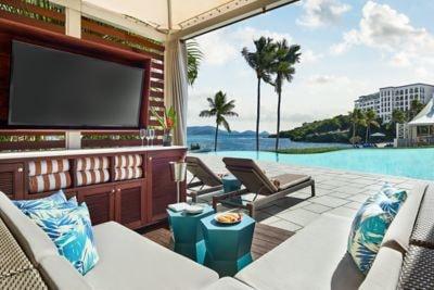 Poolside cabana with chairs, daybed, and TV