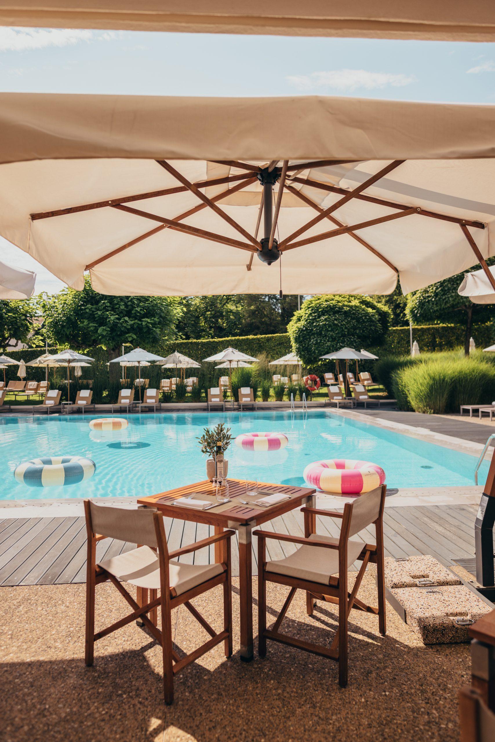 Poolside restaurant at InterContinental Geneva, wooden terrace and outdoor pool surrounded by greenery