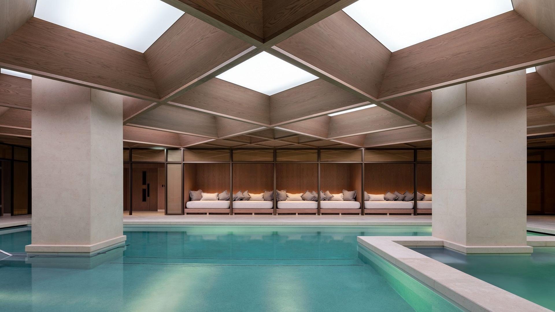 Indoor pool with sofa beds and square roof design with lightning at The Retreat Spa in The Londoner Hotel