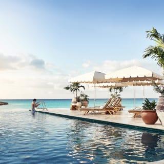 Outdoor infinity pool surrounded by potted plants overlooking a bay