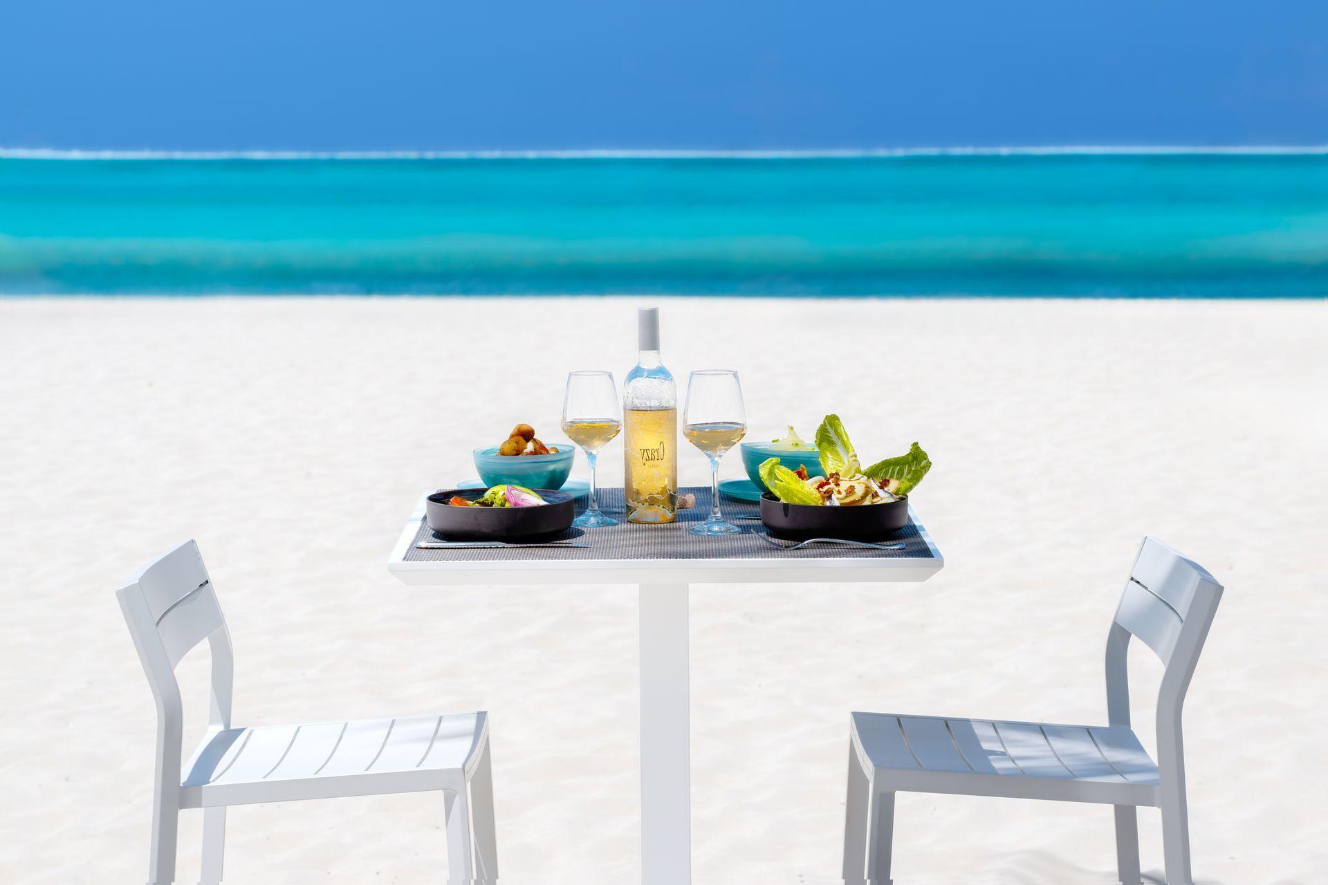 A table on the beach with a bottle of wine on it