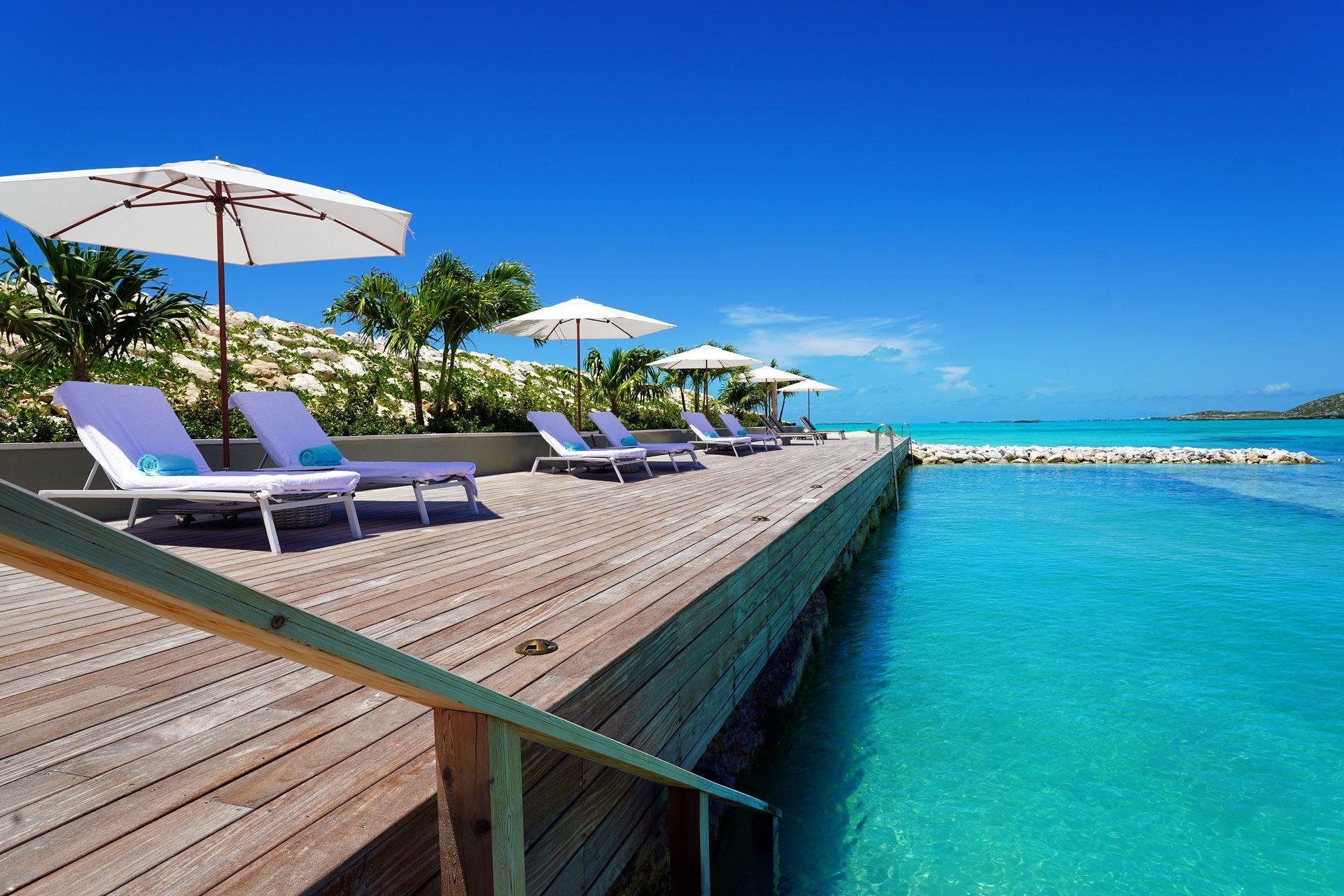 A wooden deck with chairs and umbrellas overlooking the ocean