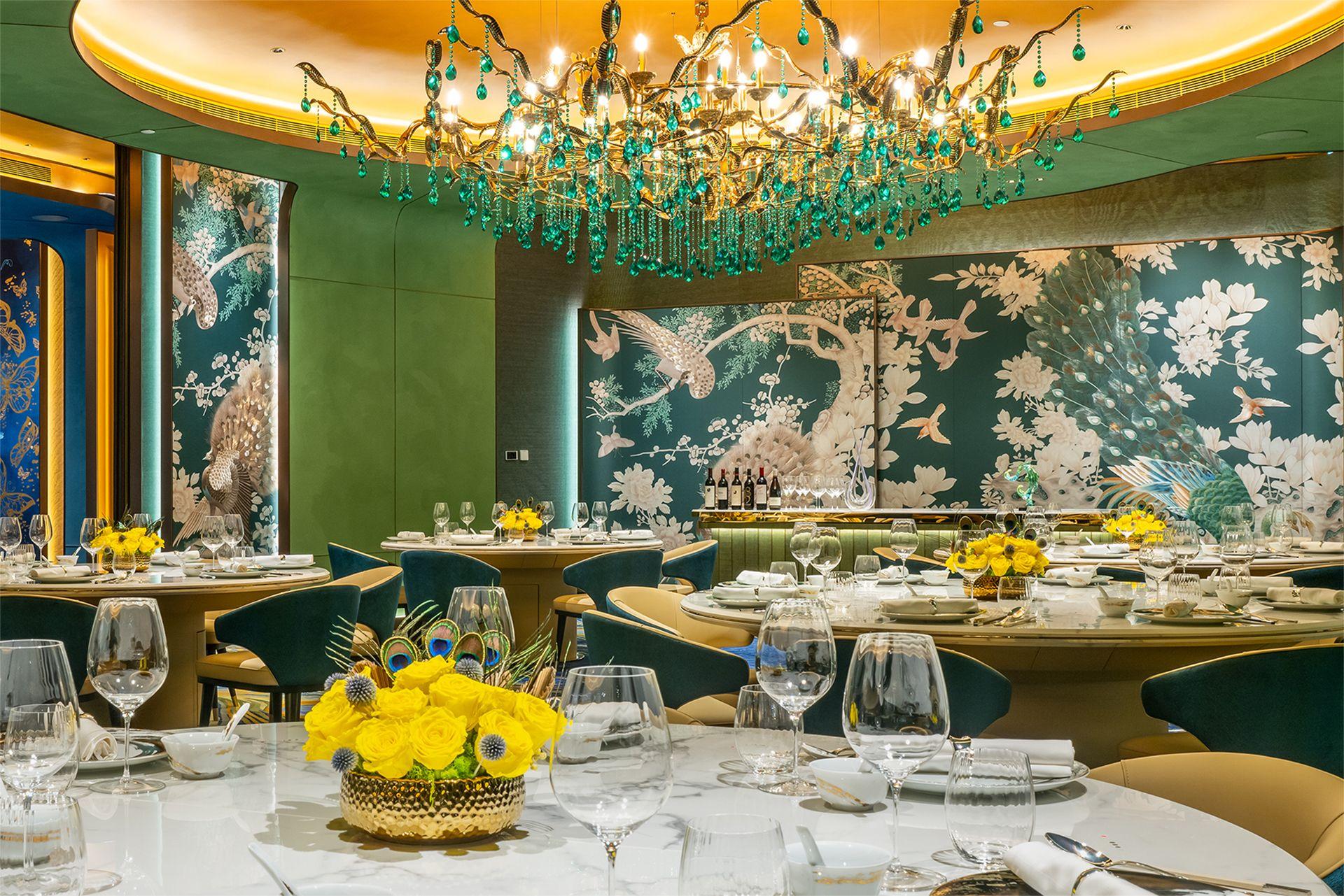 The green‑themed Grand Imperial Court blends traditional Chinese grandeur with refined contemporary design. Deep emerald and peacock‑blue tones anchor the room, complemented by a golden dome light feature, hand‑painted floral wall panels, and a shimmering chandelier that adds dimensional elegance. The round table layout and luxurious furnishings create an intimate, palace‑inspired atmosphere ideal for prestigious banquets, celebratory gatherings, and elevated Chinese dining experiences.