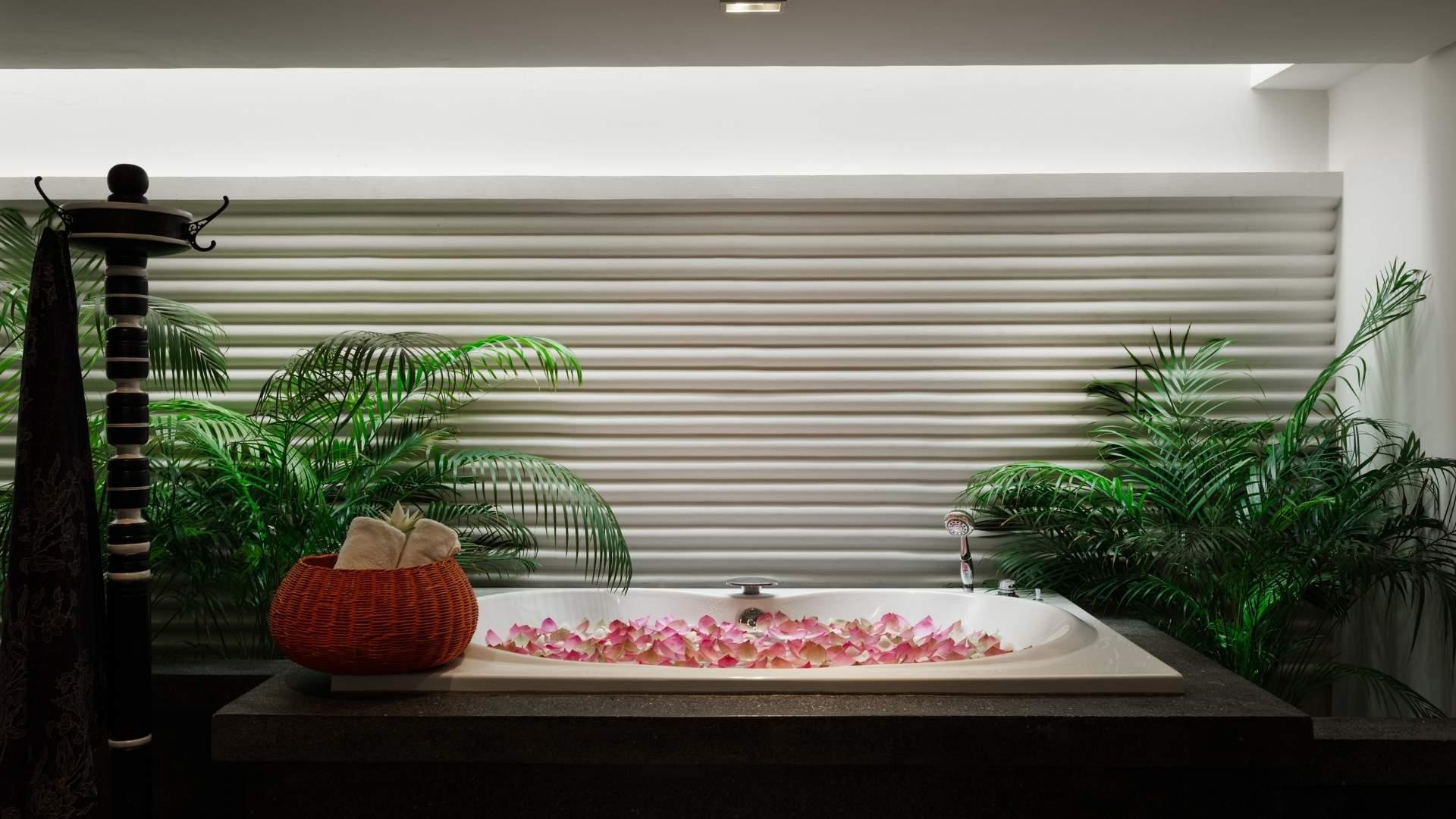 Spa bathtub with rose petals and tropical plants at Shinta Mani Angkor, creating a serene wellness retreat.