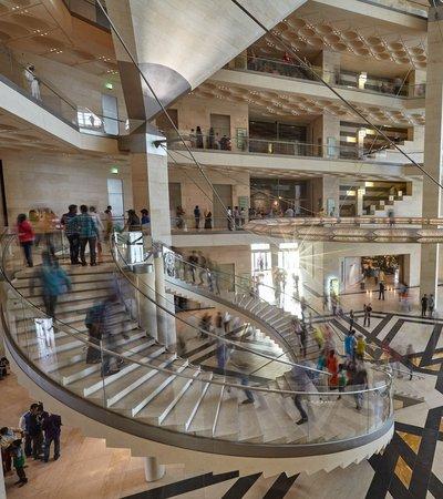 Atrium space with curved staircases at the Museum of Islamic Art, busy with museum visitors