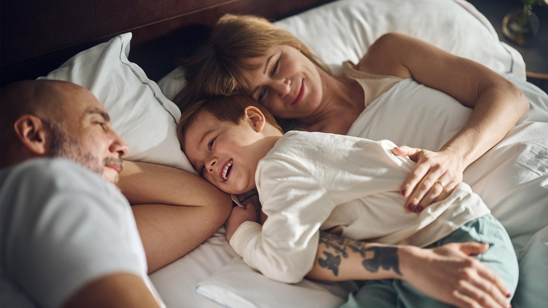 Familj ligger nedbäddad i säng på hotellet.