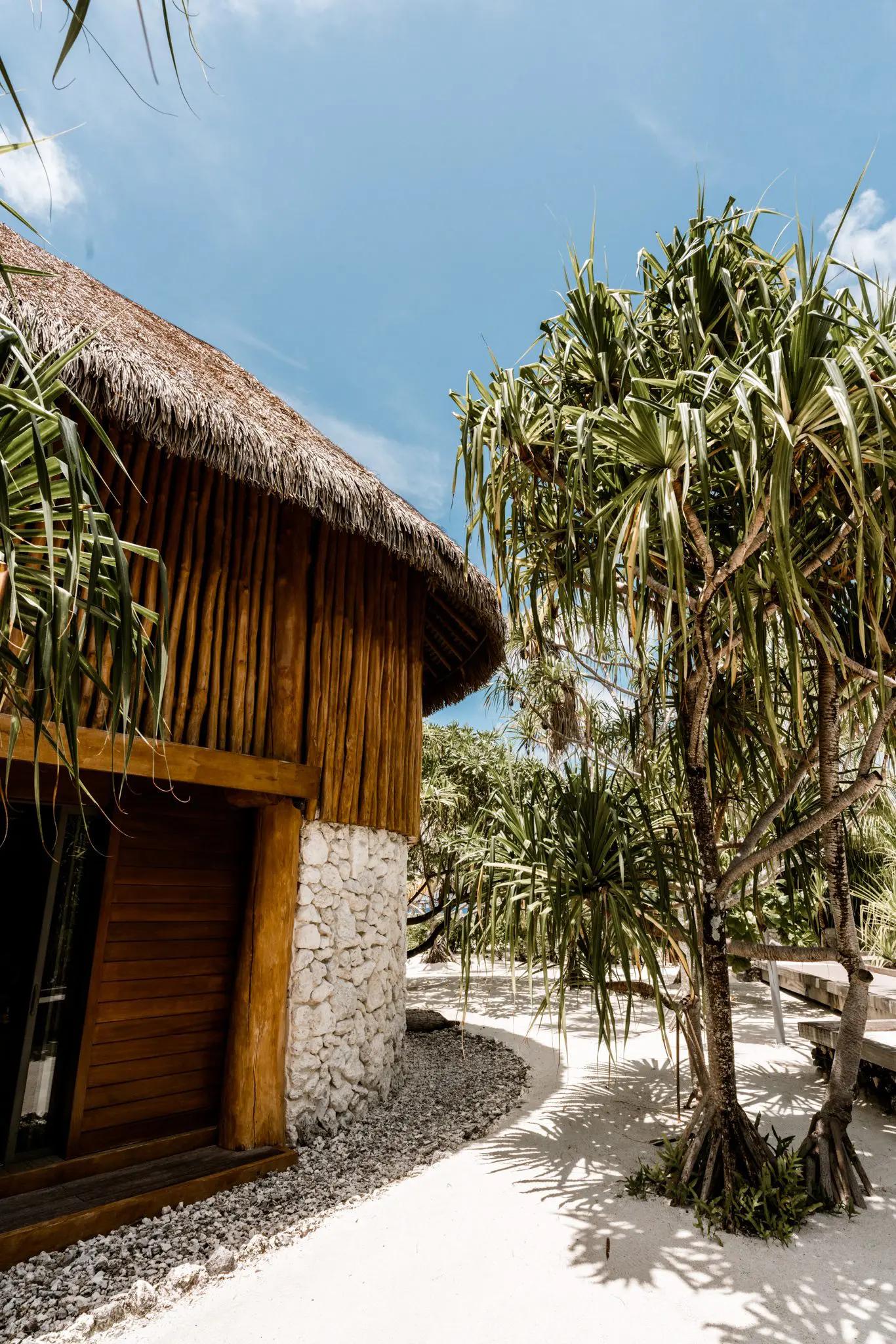 Round building with a stick and stone exterior, surrounded by sand and palms at our Tahitian all inclusive resort