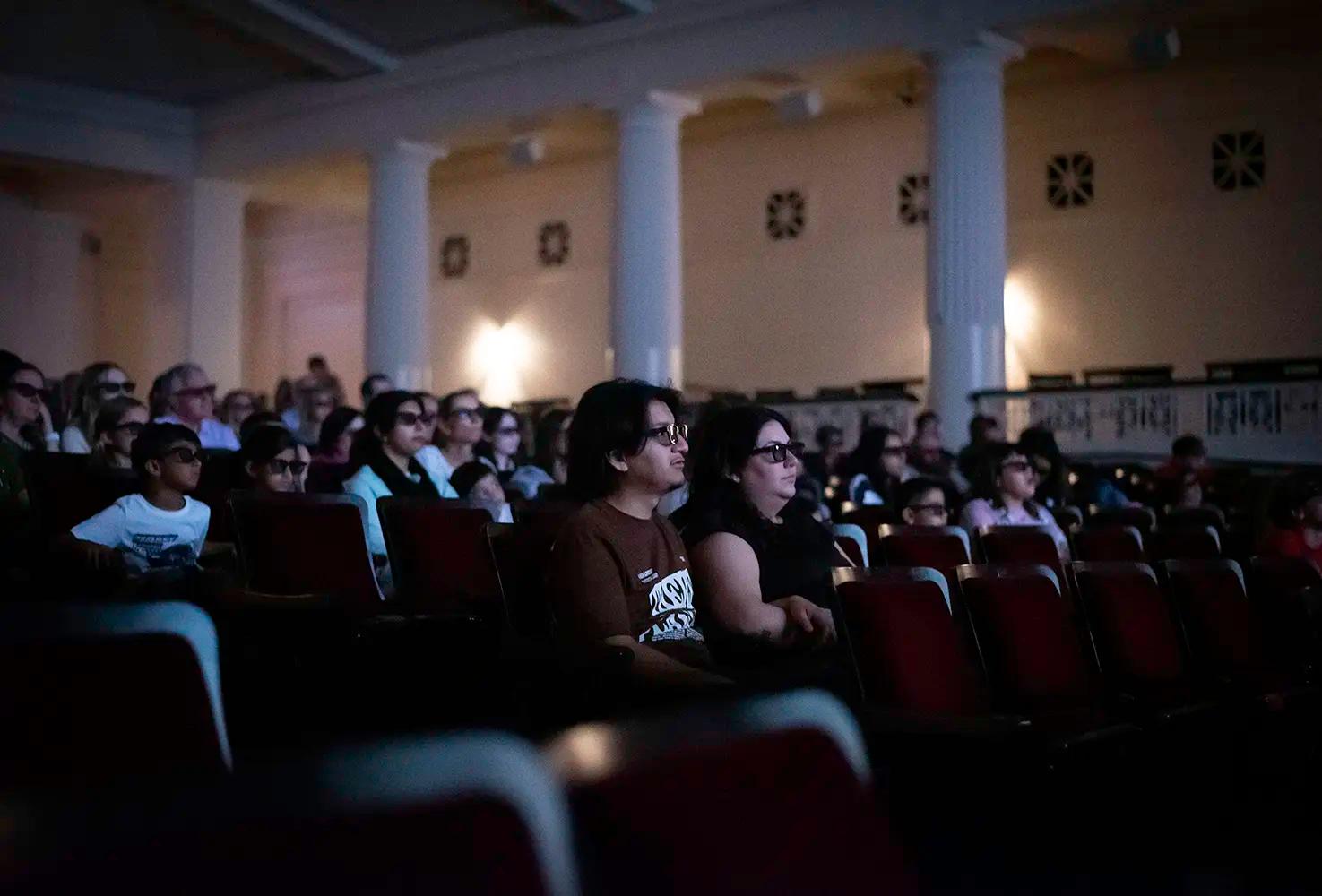 Visitors wearing 3D glasses seated in a theater.